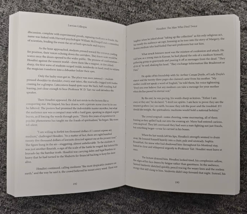 An open Trade Paperback Edition rests on a gray, textured fabric, displaying two pages from a story about the Houdini death, with a hand holding down the left page.